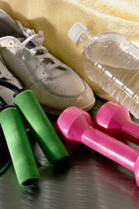 close-up on an athletic shoe, water bottle, free weights, and a towel