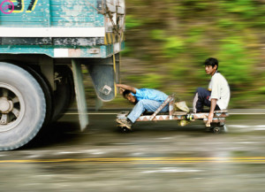 two men on small cart pulled behind truck