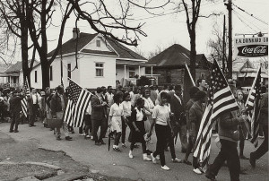 Black and white people, some carrying American flags, marching in the ...