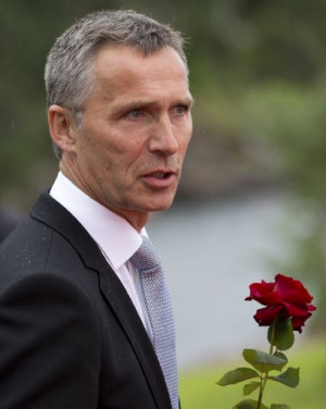 Norway's Prime Minister Jens Stoltenberg holds a flower on his way to ...