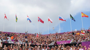 Spectators soak up the sun during the Beach Volleyball competition