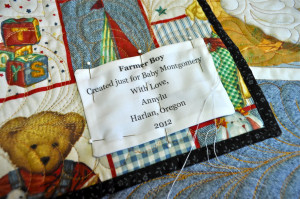 stitching the label onto the back of the baby quilt ...
