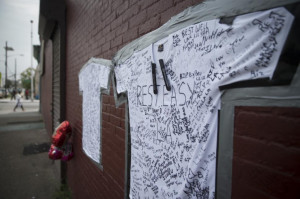 shirts covered with written messages are taped on a wall at memorial ...