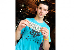 Travis showing a $1 bill autographed by Travis Pastrana