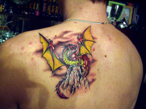 ... yellow wings which sits on a rock tattoo on shoulder blade of a man