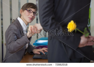flirting in office - man holding flower behind his back - stock photo