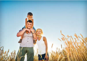 Child on fathers shoulders next to mother in wheat field