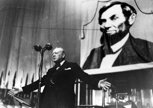 Winston Churchill speaking in front of a portrait of Abraham Lincoln