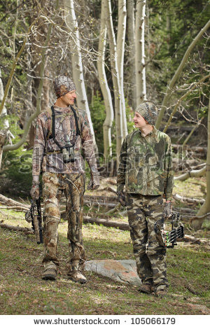 father and son walking together outdoors with archery hunting gear