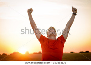 Successful man raising arms after cross track running on summer sunset ...