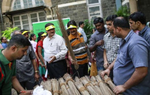 Employees from various departments collect brooms before a cleanliness ...