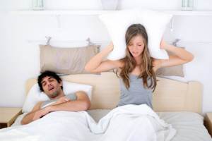 Woman covering her ears while boyfriend snores
