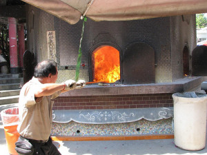 Re-arranging the ashes in the ghost money burner.