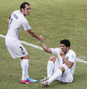 Image: Uruguay's Luis Suarez,right, holds his teeth while sitting on ...