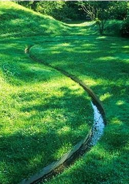 Land sculpting - Winding rill through grass in undulating garden with ...