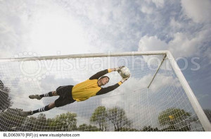 Hispanic soccer goalie catching soccer ball in air