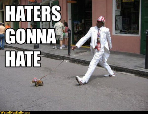 Man in white suite walking little dog: Haters gonna hate