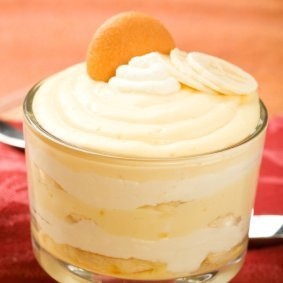 Cup of banana pudding topped with whipped cream and a vanilla wafer ...