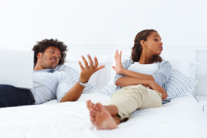 ... young unhappy African American couple lying on the bed and arguing