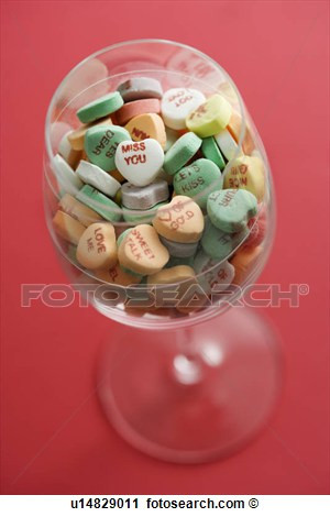 Wine glass full of colorful candy hearts with sayings on them on red ...