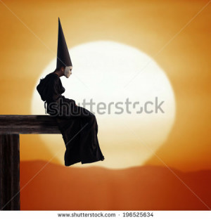 ... of a strange person in black cloak and dunce hat at sunset
