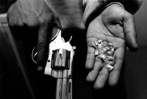gangster holds the tools of his trade: a gun and dime bags of crack ...