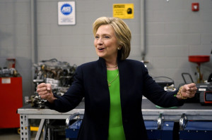 Former U.S. Secretary of State Clinton pumps her fists in an auto shop ...