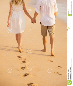 Stock Images: Romantic couple holding hands walking on beach at sunset