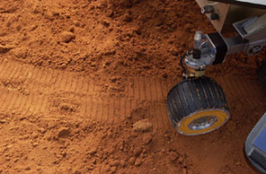 Image right: A replica rover makes tracks at a display in front of the ...