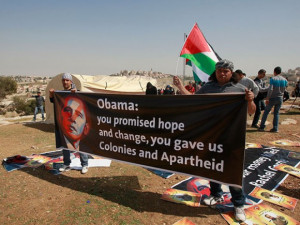 activists hold posters with the photo of President Barack Obama ...
