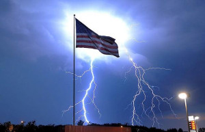 Lightning strikes behind an American flag during a thunderstorm in ...
