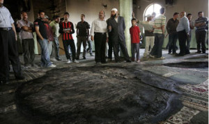 Palestinians inspect the damage following a fire inside a mosque in ...