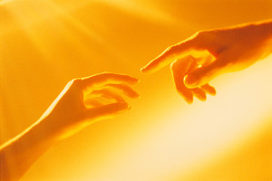 Male and female hand nearly touching each other in a golden glow