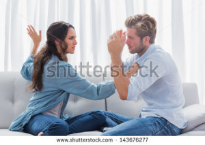 Upset woman about to slap her partner the living room - stock photo