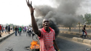 protester in front of a burning tyre in Lagos, Nigeria (January 2012 ...
