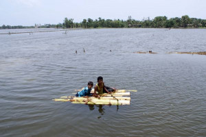 Two people use a raft made of the trunks of several banana trees