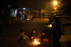 Children sit around a small bonfire on a cold night in New Delhi ...