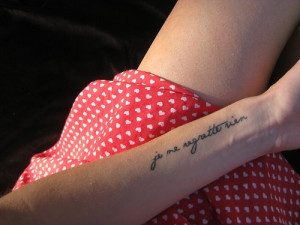 regret nothing” quote tattoo written in French on girls arm