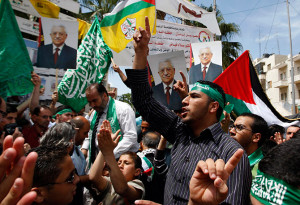 young hamas activist marches while holding a hamas flag