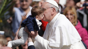 Pope Francis kisses a child as he leaves after celebrating his first ...