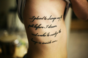 ... quote tattoo on this girls side / ribcage in a wide black cursive font