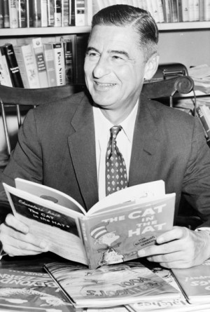 Ted Geisel (Dr. Seuss) half-length portrait, seated at desk covered ...