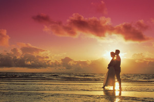 Couple embraces romantically on the beach during a beautiful sunset.