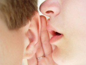Image of a person whispering in someone else's ear.