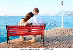 ... -love-couple-sitting-on-a-bench-by-the-sea-embracing-149367269.jpg