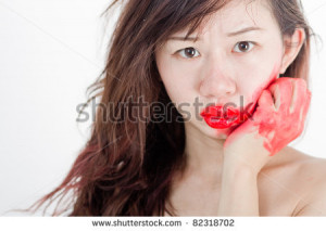... hair Asian girl with red lip lipstick smother her cheek face hand