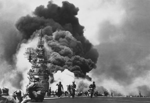 Flames leap from the deck of the USS Bunker Hill, after it was hit by ...