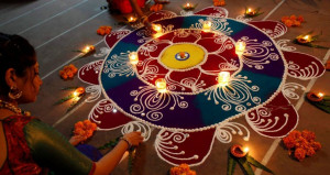 Hindu women arrange oil lamps and flowers around a 'Rangoli', a ...