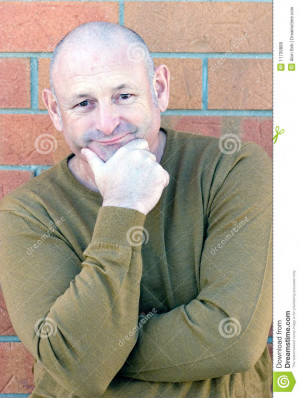Portrait of a handsome middle aged man standing next to a brick wall.