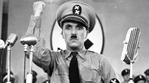 Charlie Chaplin, verkleidet als Adolf Hitler, steht vor Mikrofonen und ...